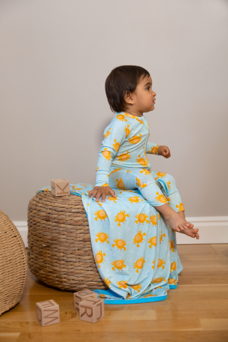 Baby sitting on a blue blanket wearing a Kibby bamboo pyjamas
