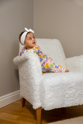 Baby sitting in an armchair wearing a flower pattern bamboo pyjamas